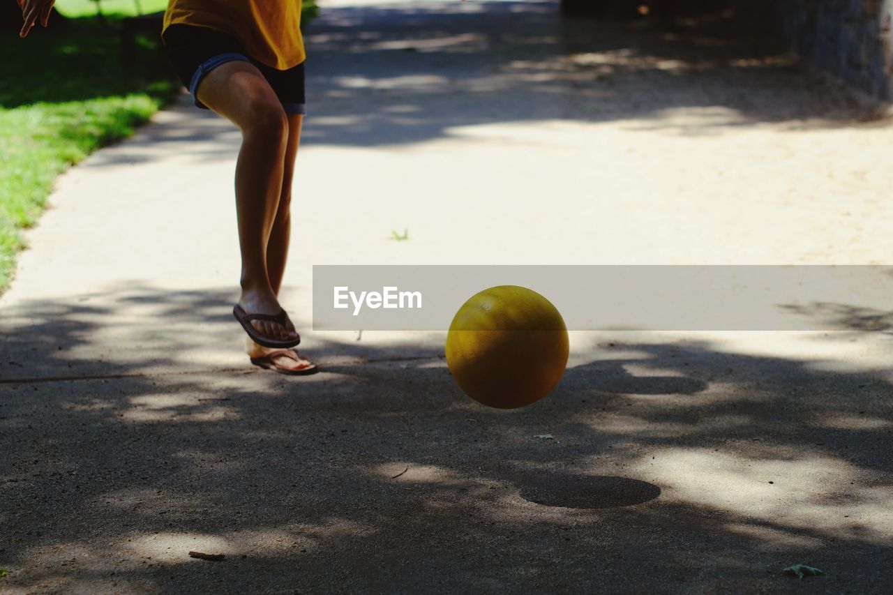 Low section of woman playing with ball on street