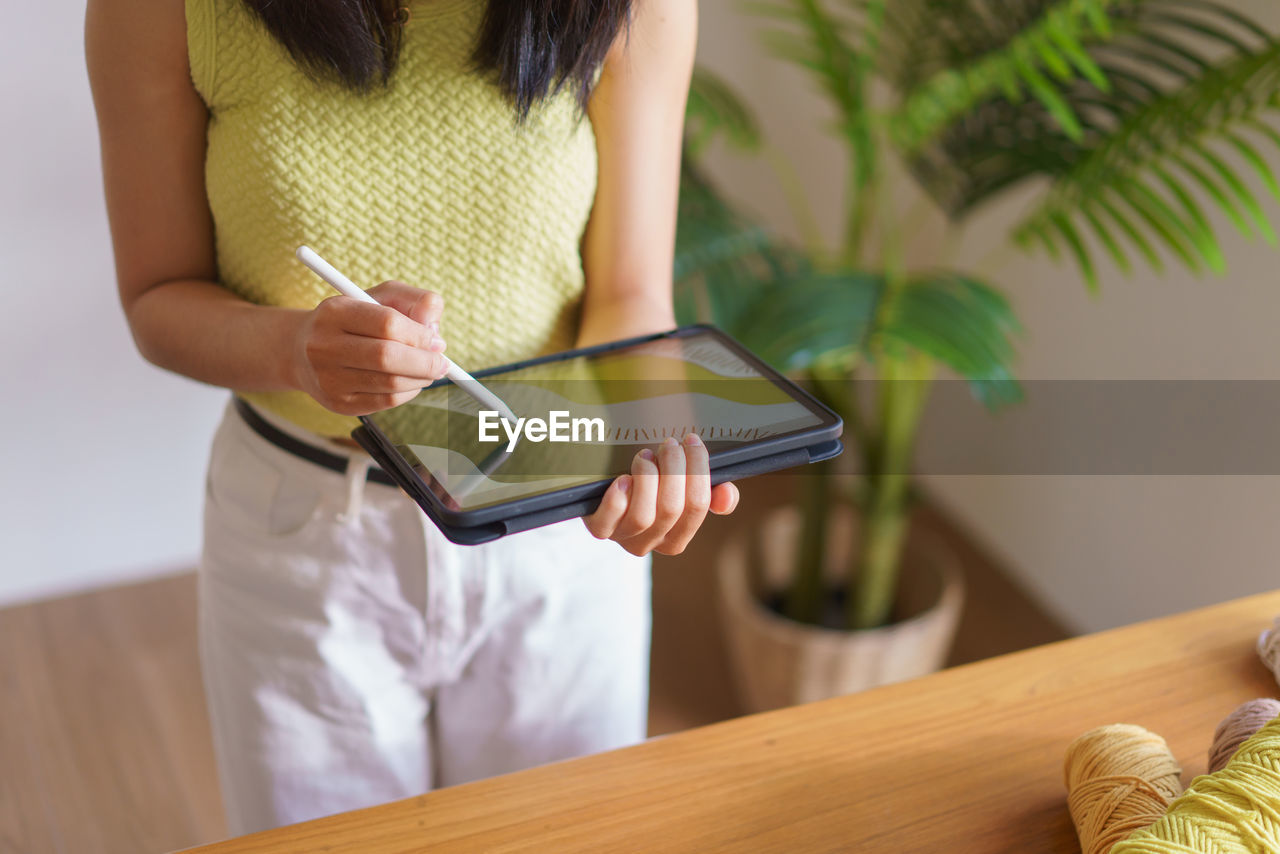 midsection of woman using digital tablet