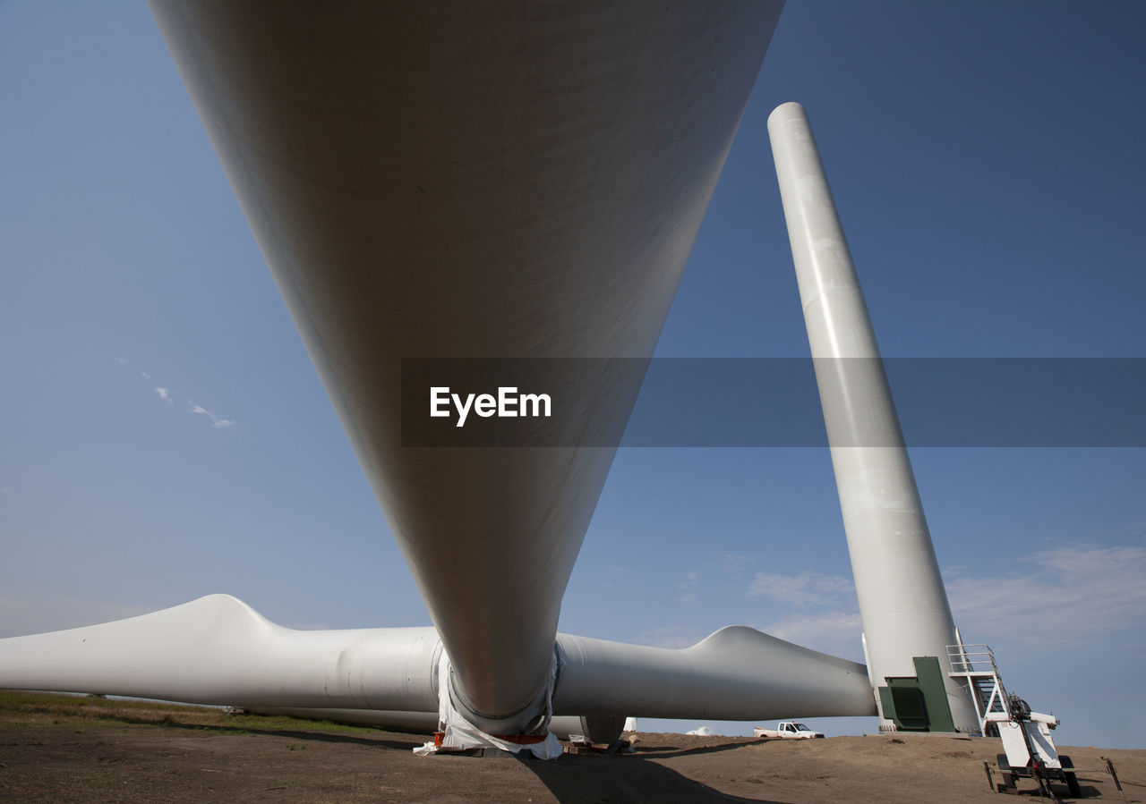 Wind turbines installing on field against clear blue sky during sunny day