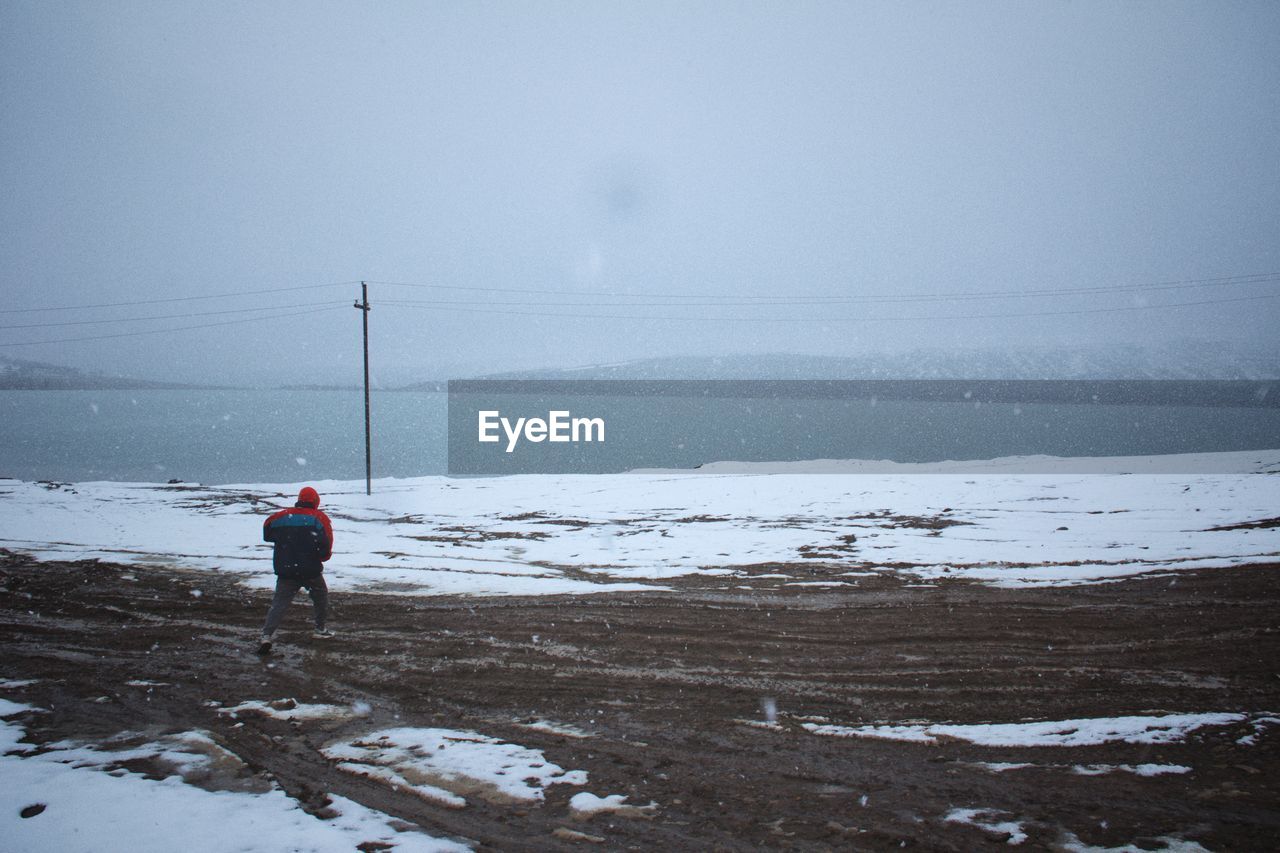 rear view of man walking at beach