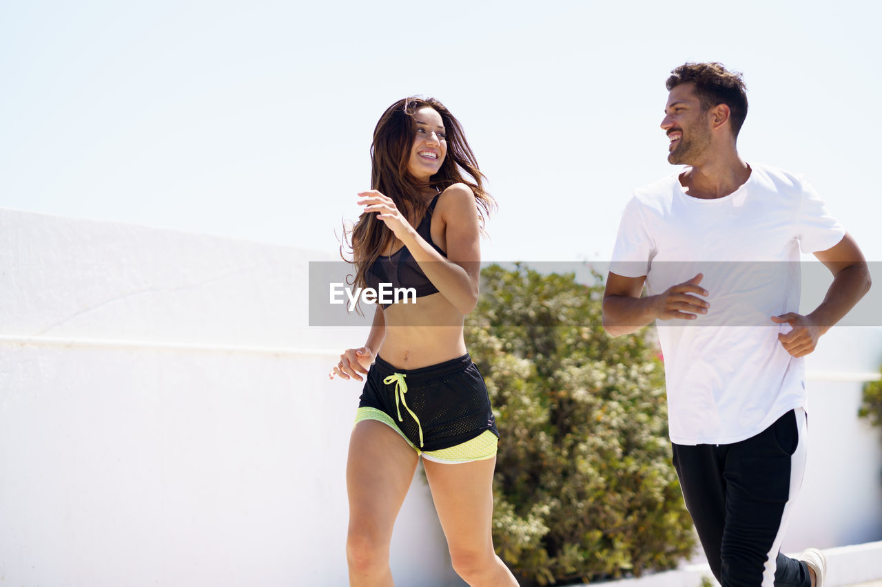 Couple jogging against clear sky