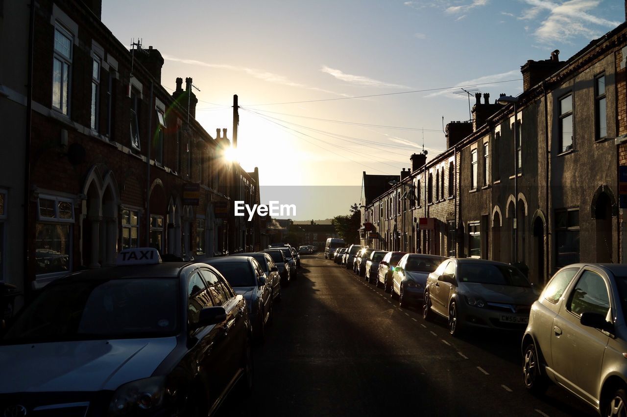 Cars on street in city against sky during sunset