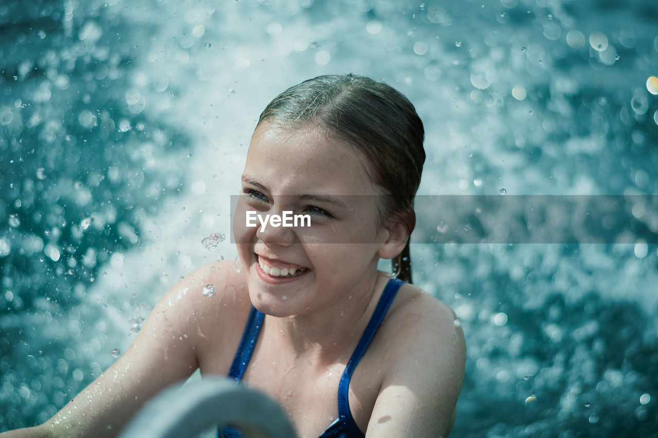 PORTRAIT OF A SMILING MAN SWIMMING IN POOL
