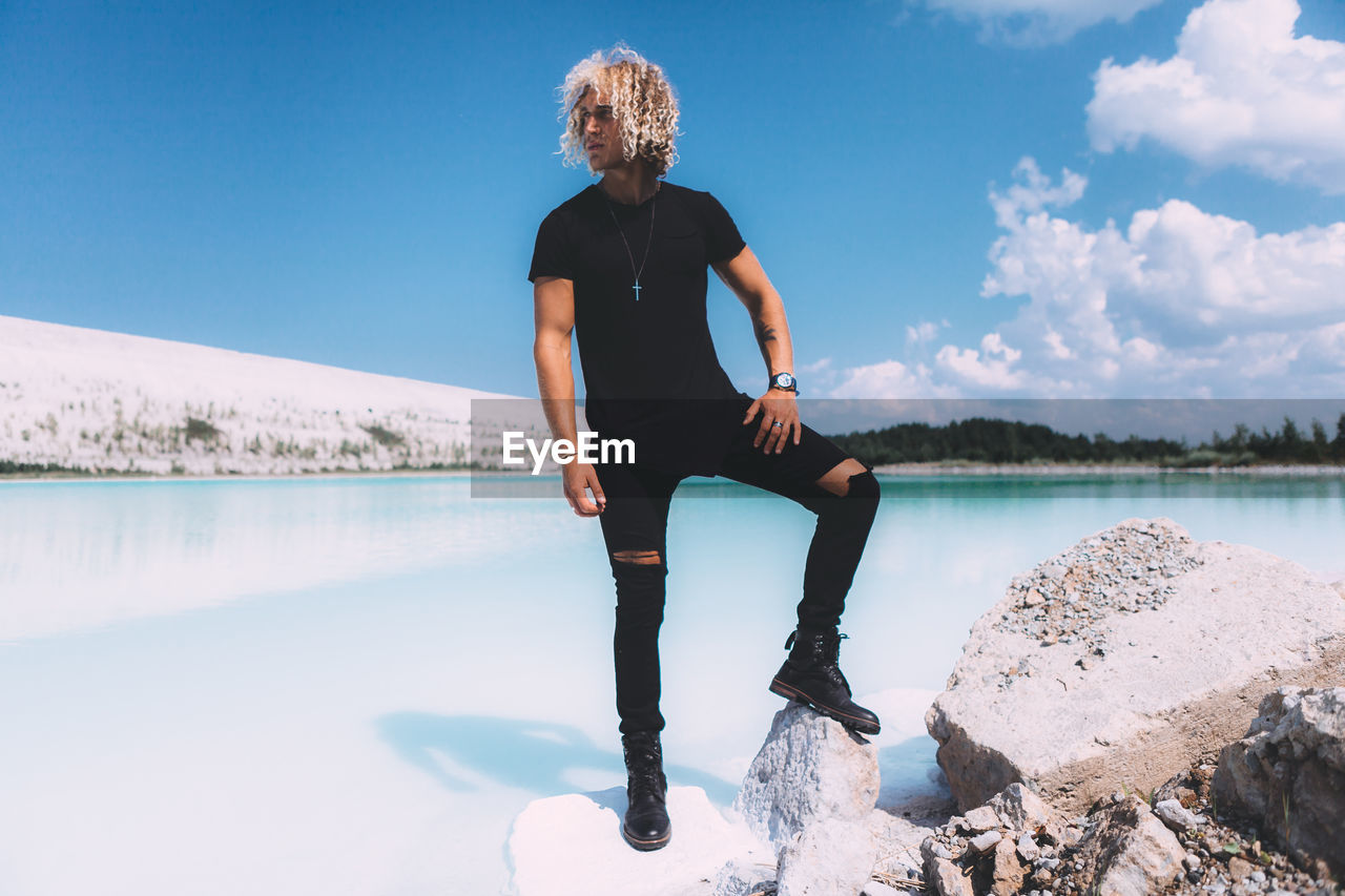 MAN STANDING IN LAKE AGAINST SKY