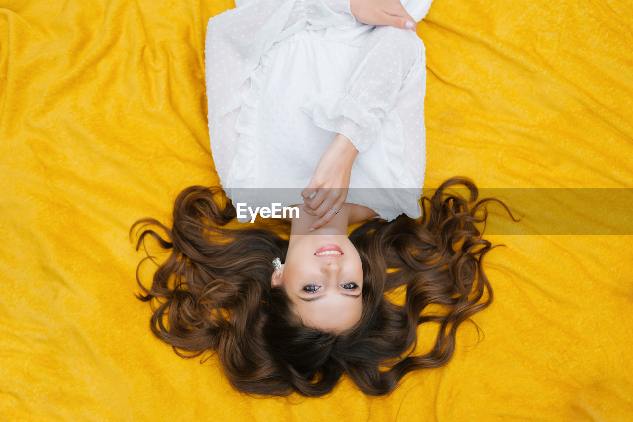 Top view of a happy white girl with a charming snow-white smile on a yellow background