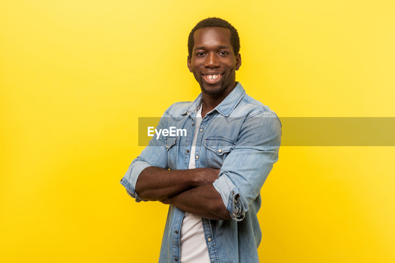 PORTRAIT OF A YOUNG MAN AGAINST YELLOW BACKGROUND
