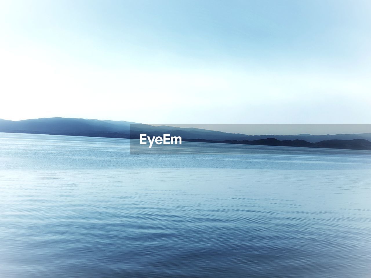 SCENIC VIEW OF SEA AND MOUNTAINS AGAINST CLEAR SKY