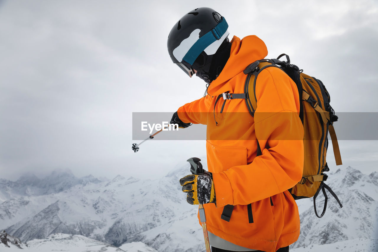 Portrait of a male skier at the top against the backdrop of epic mountains in the clouds. points