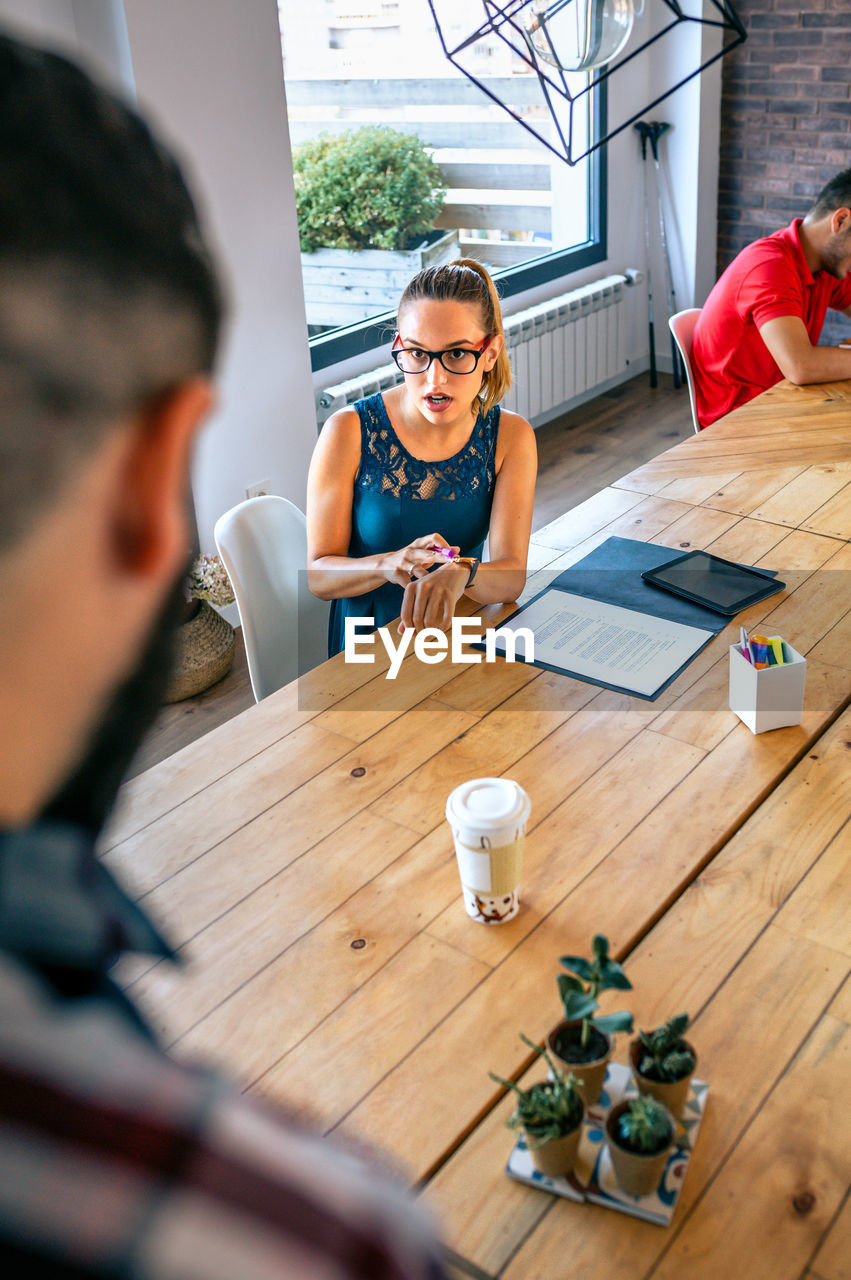 Angry female manager discussing with man for coming late to office