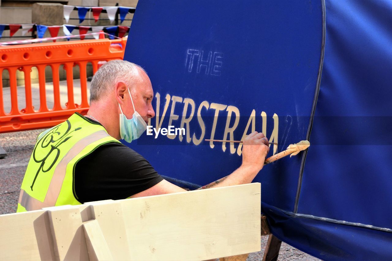 SIDE VIEW OF MAN WORKING WITH TEXT ON SEAT