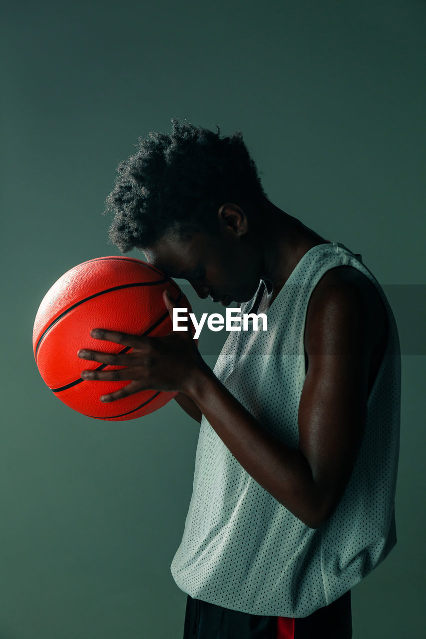 Black woman with basketball outfit in the studio using color gels and projector lights over blue background