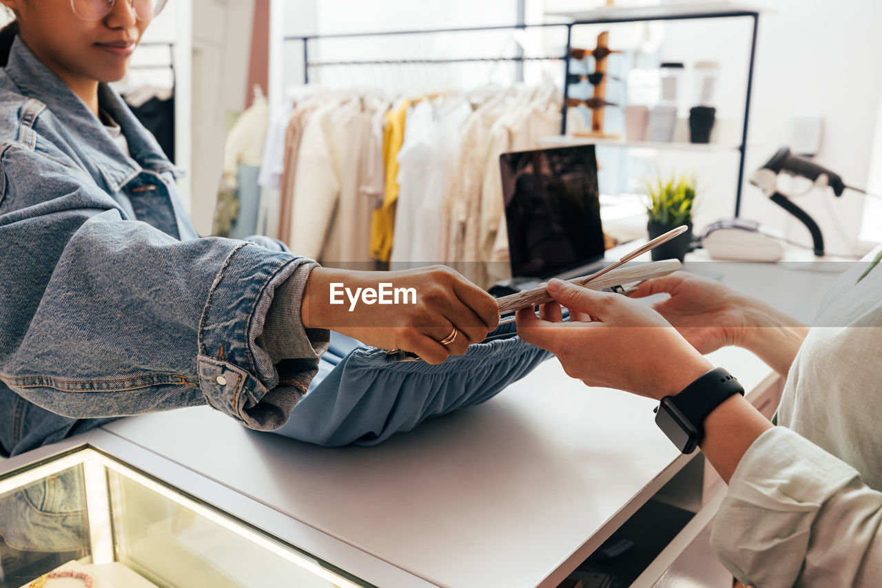 Midsection of woman holding smart phone at store