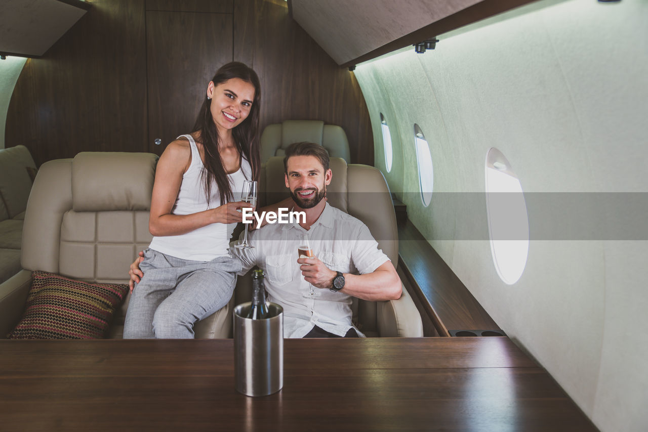 Portrait of couple drinking champagne in corporate jet