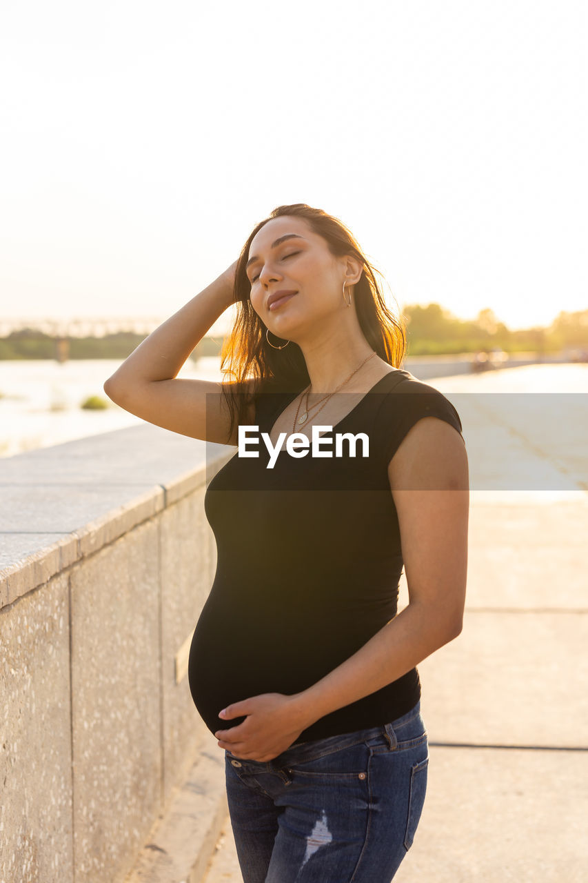 BEAUTIFUL YOUNG WOMAN STANDING AGAINST THE SKY