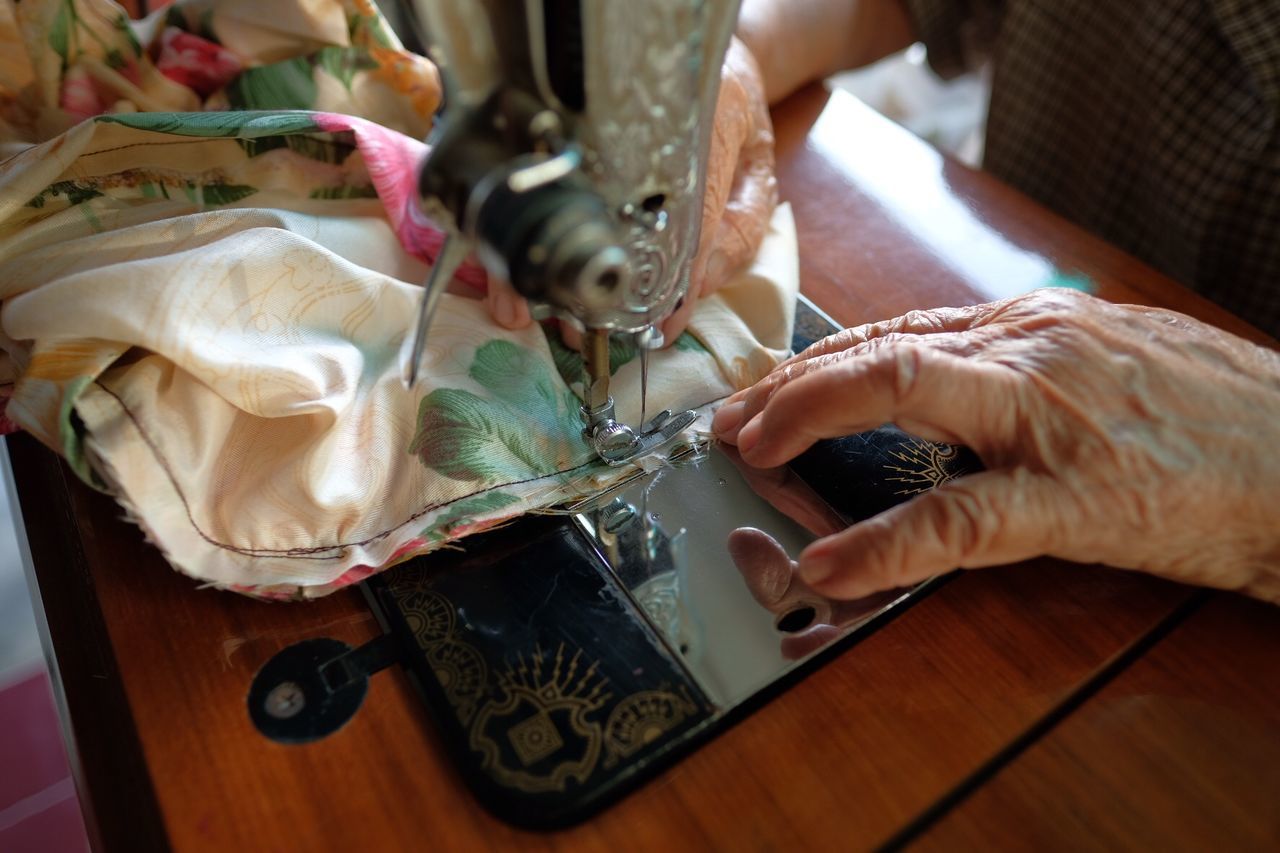 Close-up of senior tailor sewing fabric at workshop