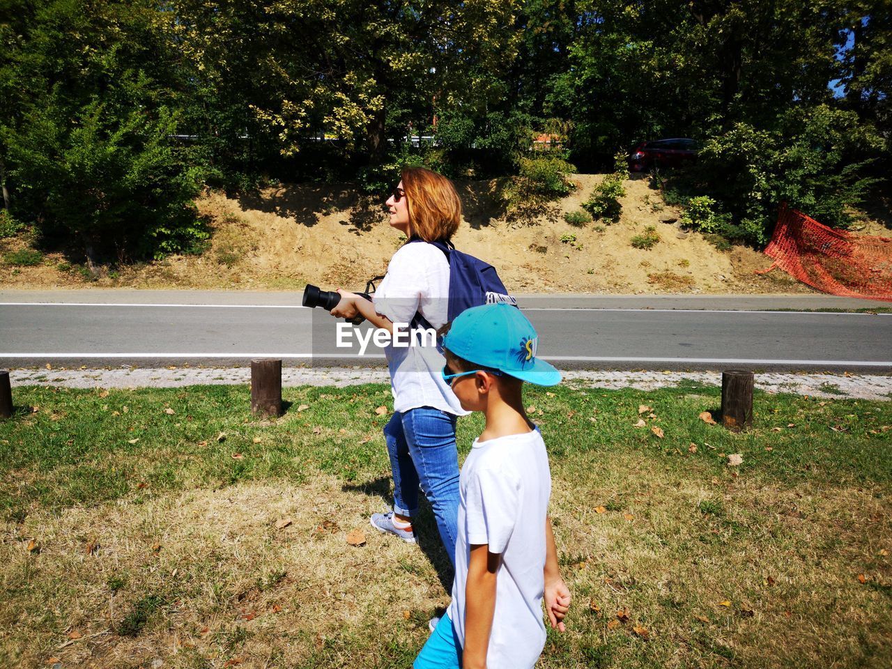 Side view of boy with mother walking on grassy field