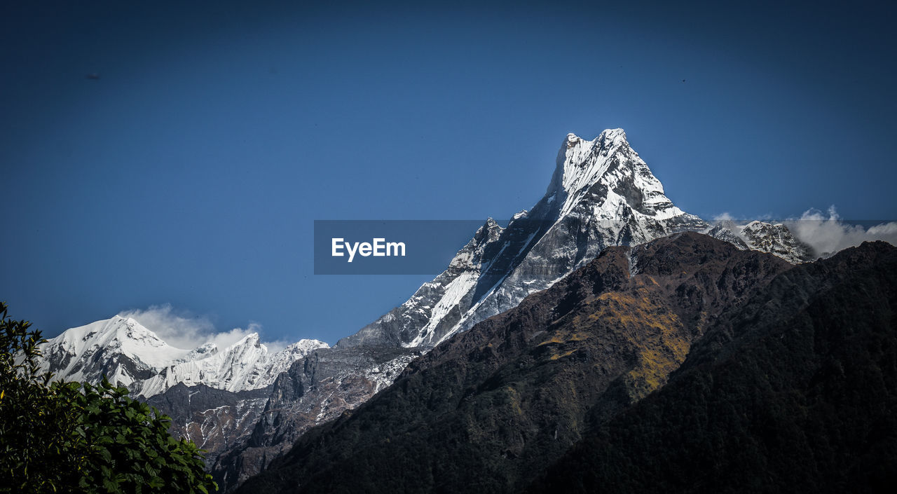 Scenic view of snowcapped mountains against clear blue sky