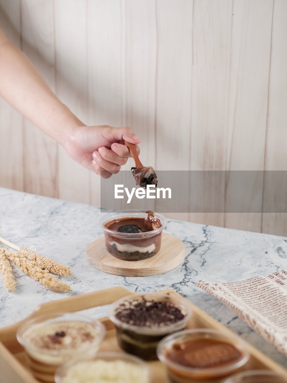 Midsection of woman take a spoon of chocolate dessert cup on table