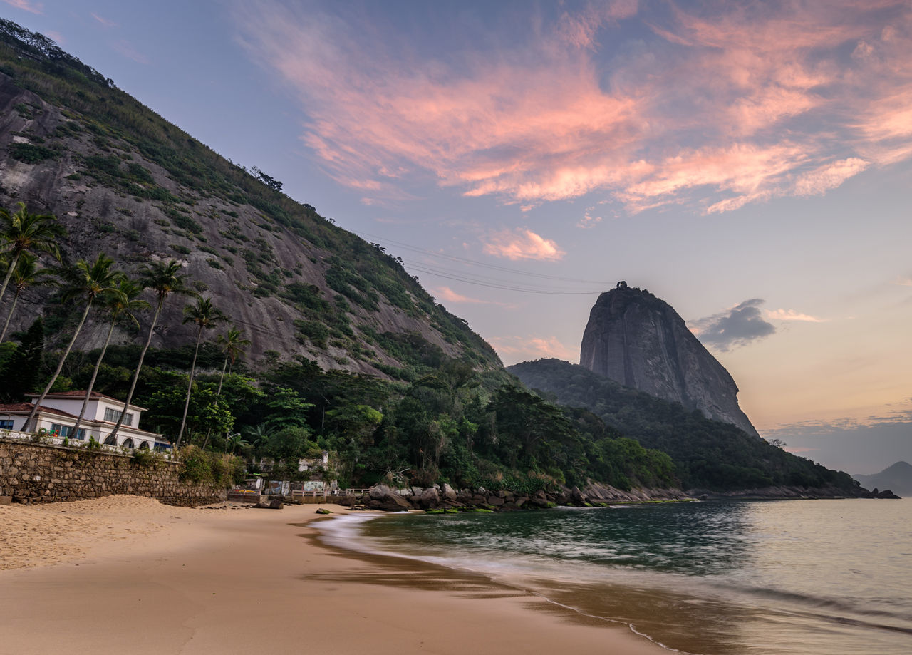 Scenic view of beach and mountain against sky at sunrise
