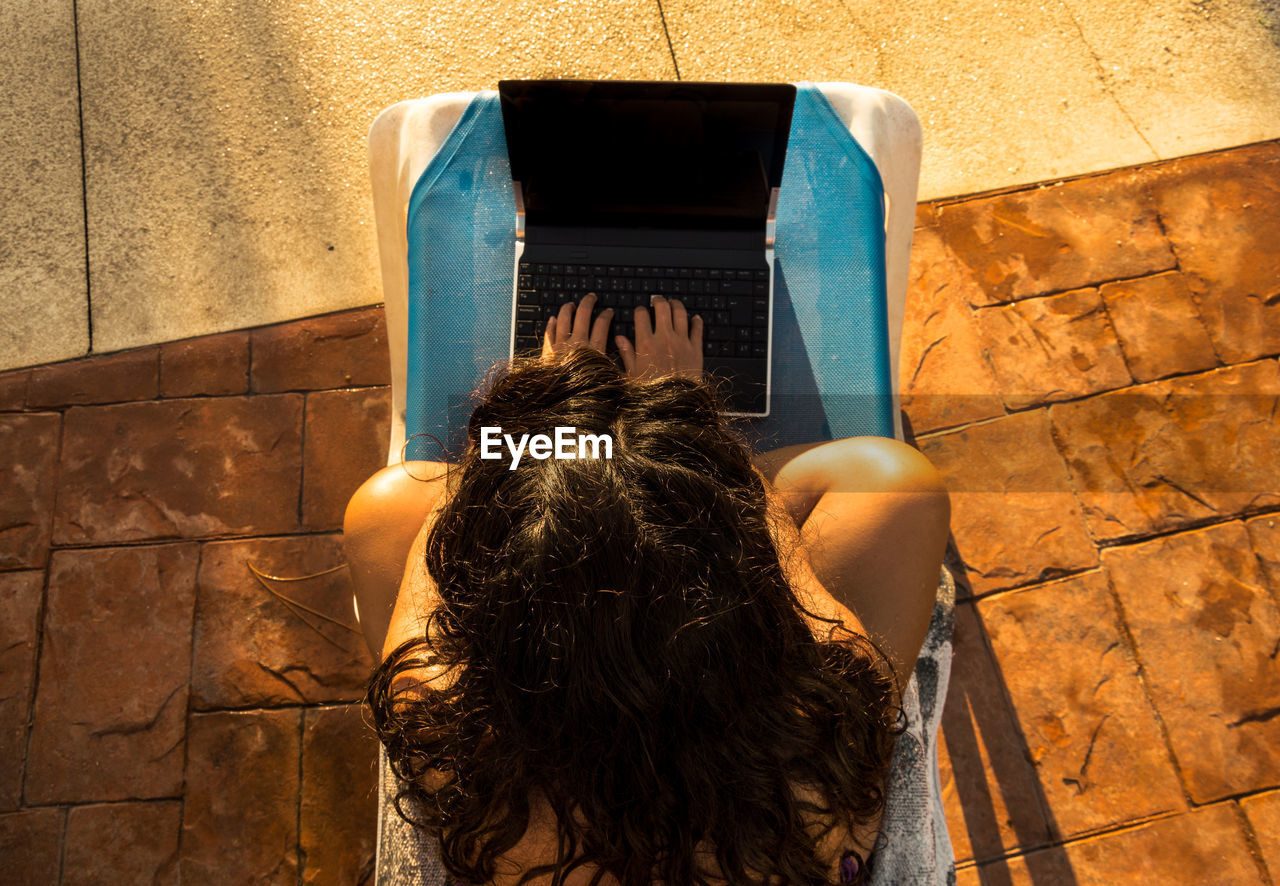 Directly above shot of woman using laptop outdoors