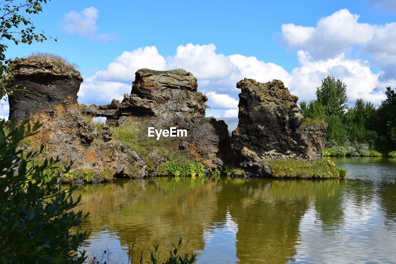 Reflection of rocks on lake myvatn against cloudy sky