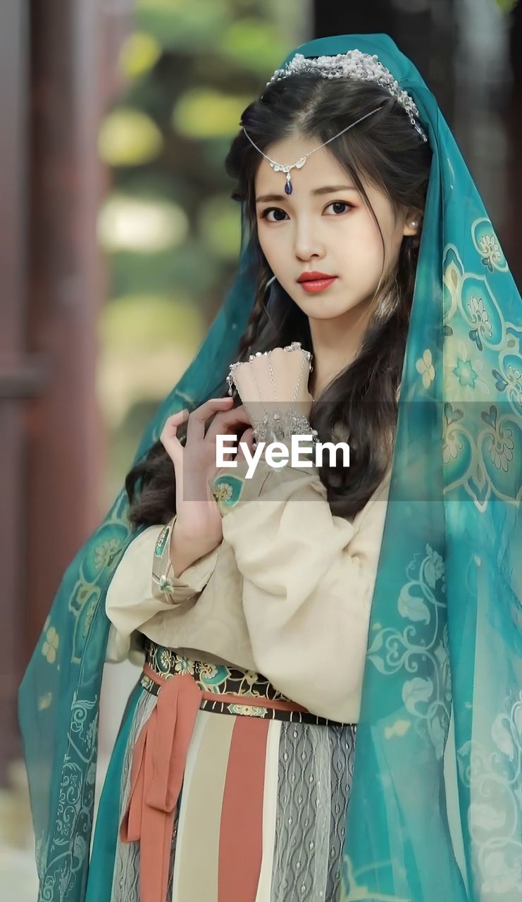 Portrait of young woman standing against blurred background