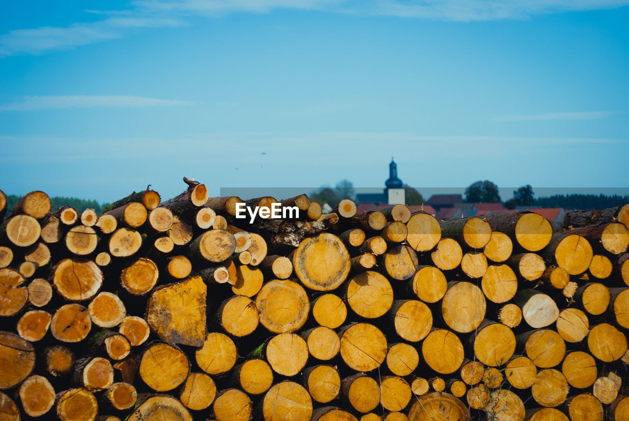 Stack of logs against sky