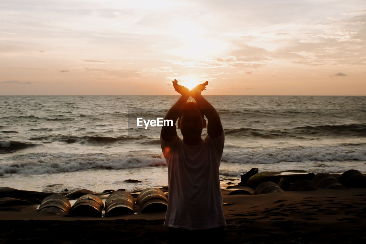 Full length of man at beach against sky during sunset