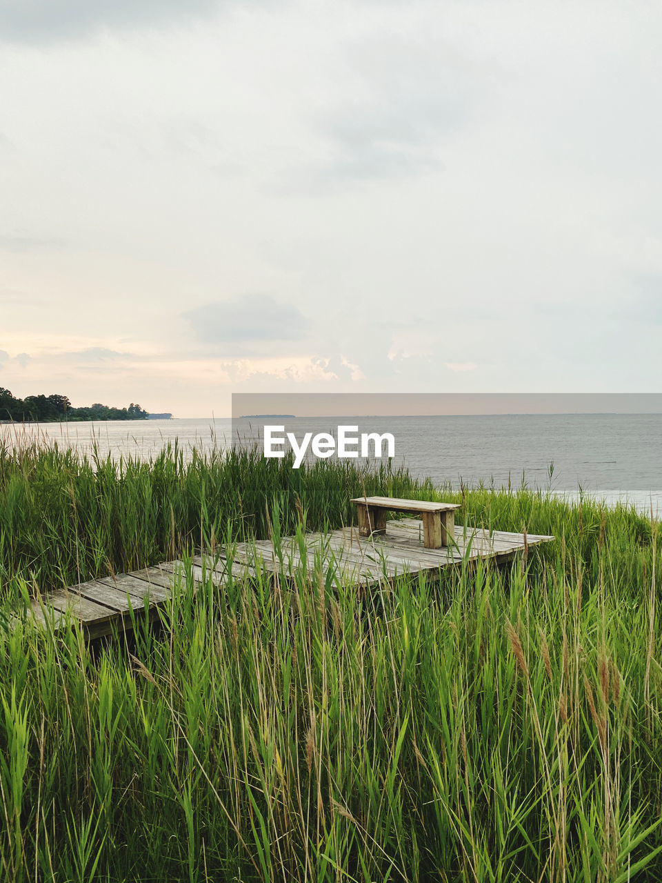 Scenic view of sea against sky with empty bench in middle