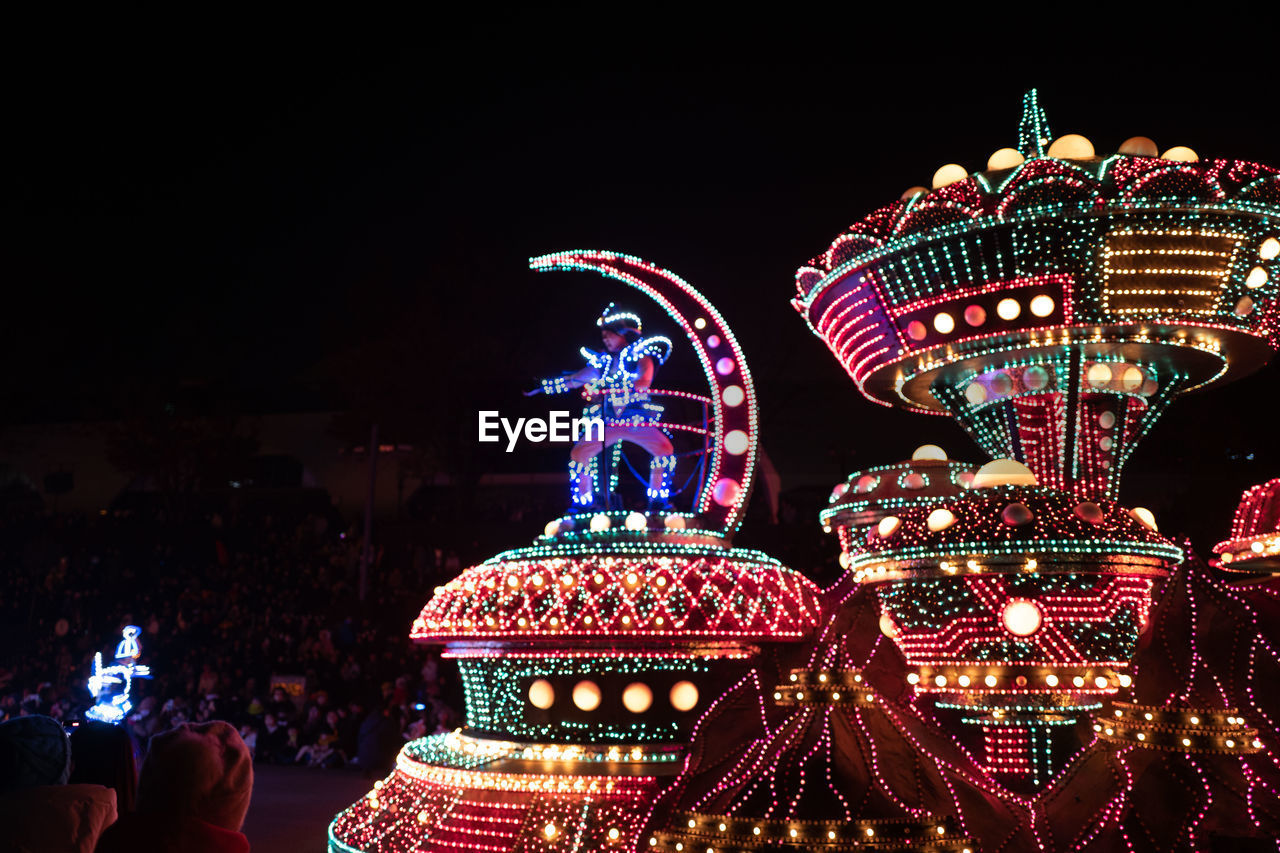 LOW ANGLE VIEW OF ILLUMINATED CAROUSEL AT NIGHT