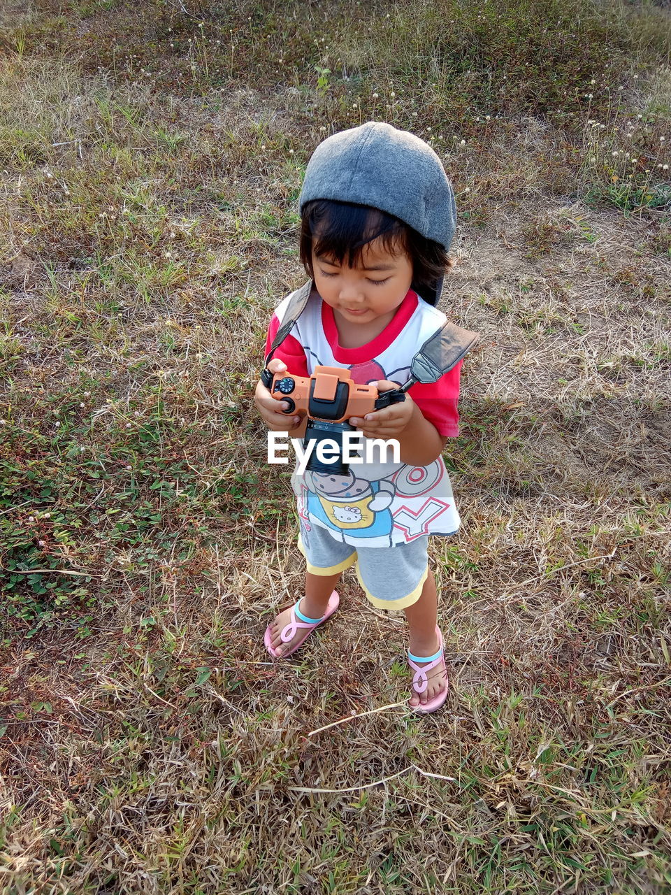 High angle view of girl holding toy camera standing outdoors