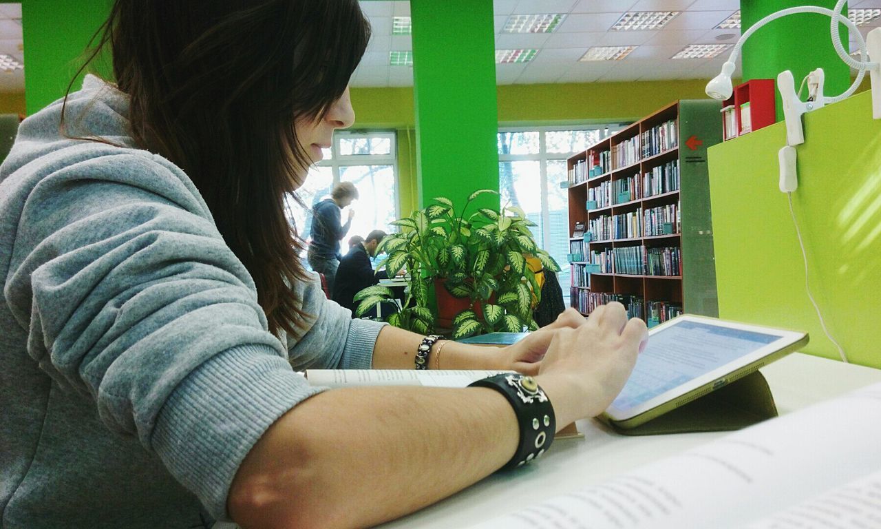 indoors, book, real people, shelf, education, learning, one person, young women, casual clothing, young adult, bookshelf, holding, library, women, day, student, freshness, adult, people