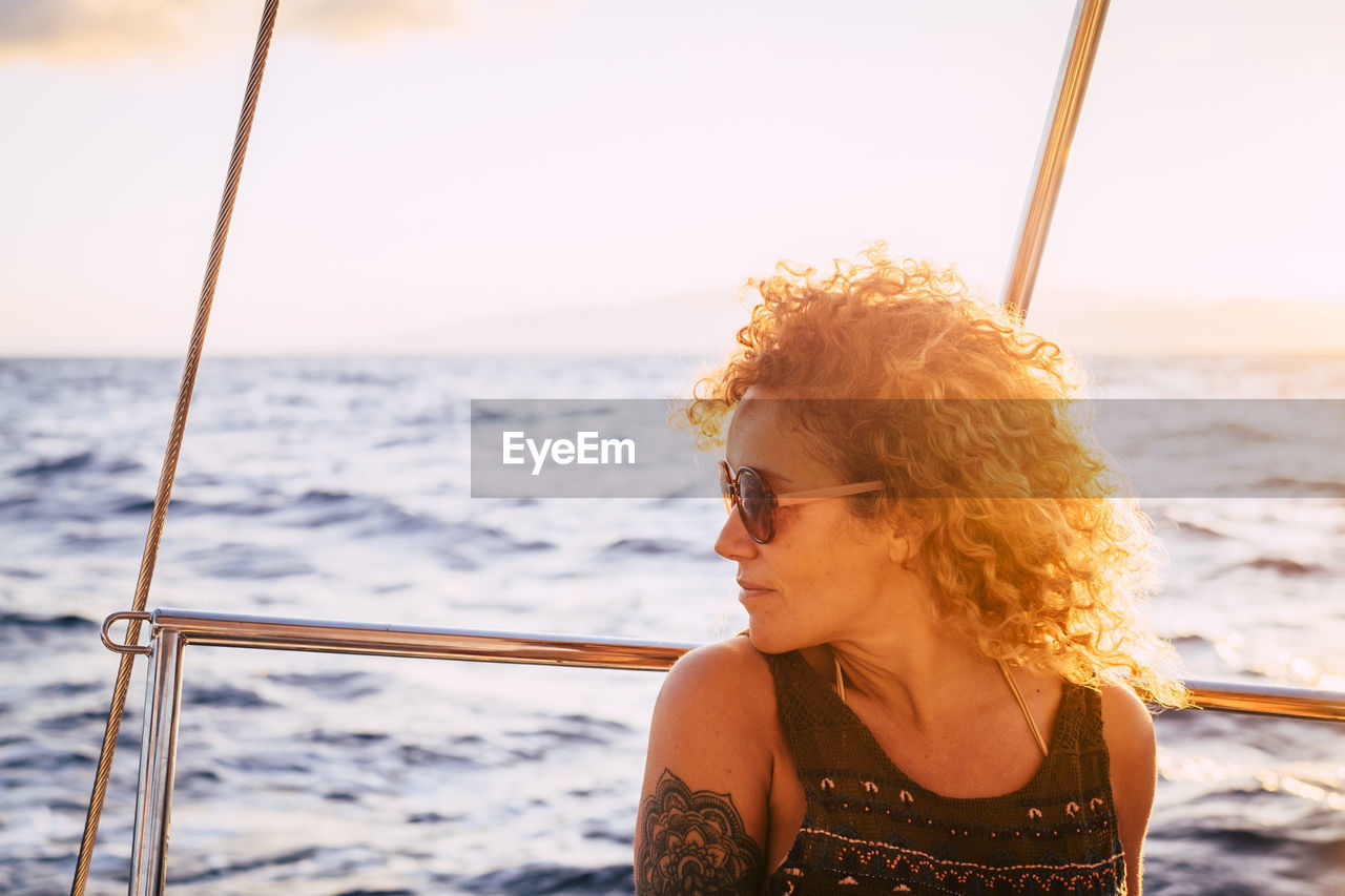 Portrait of young woman looking at sea against sky