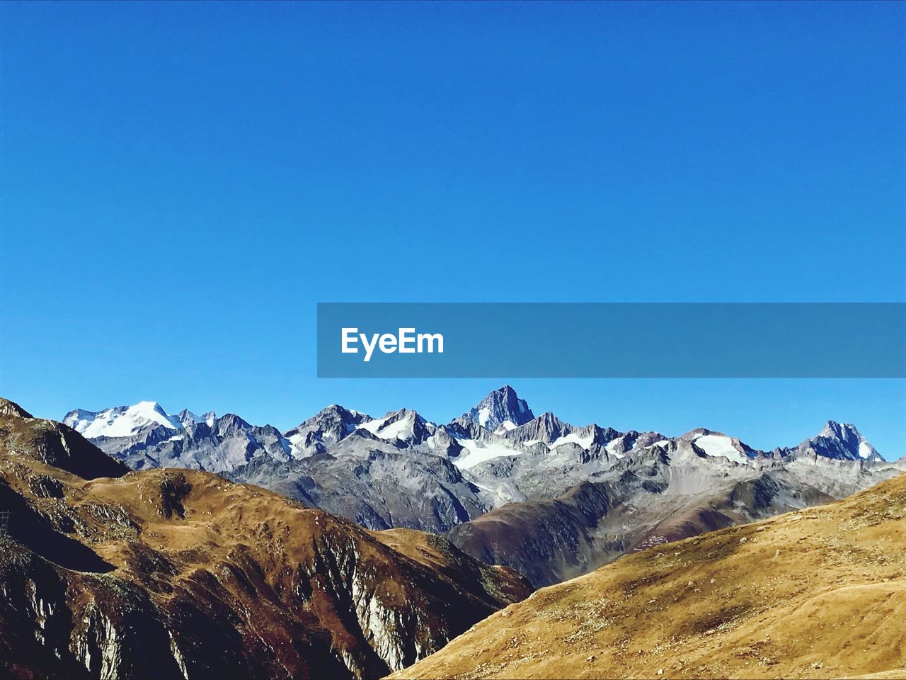 Scenic view of snowcapped mountains against clear blue sky