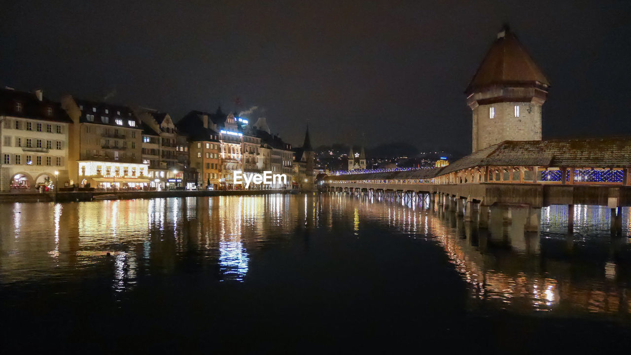 Nighttime old town lucerne, switzerland with lights reflecting in the river.