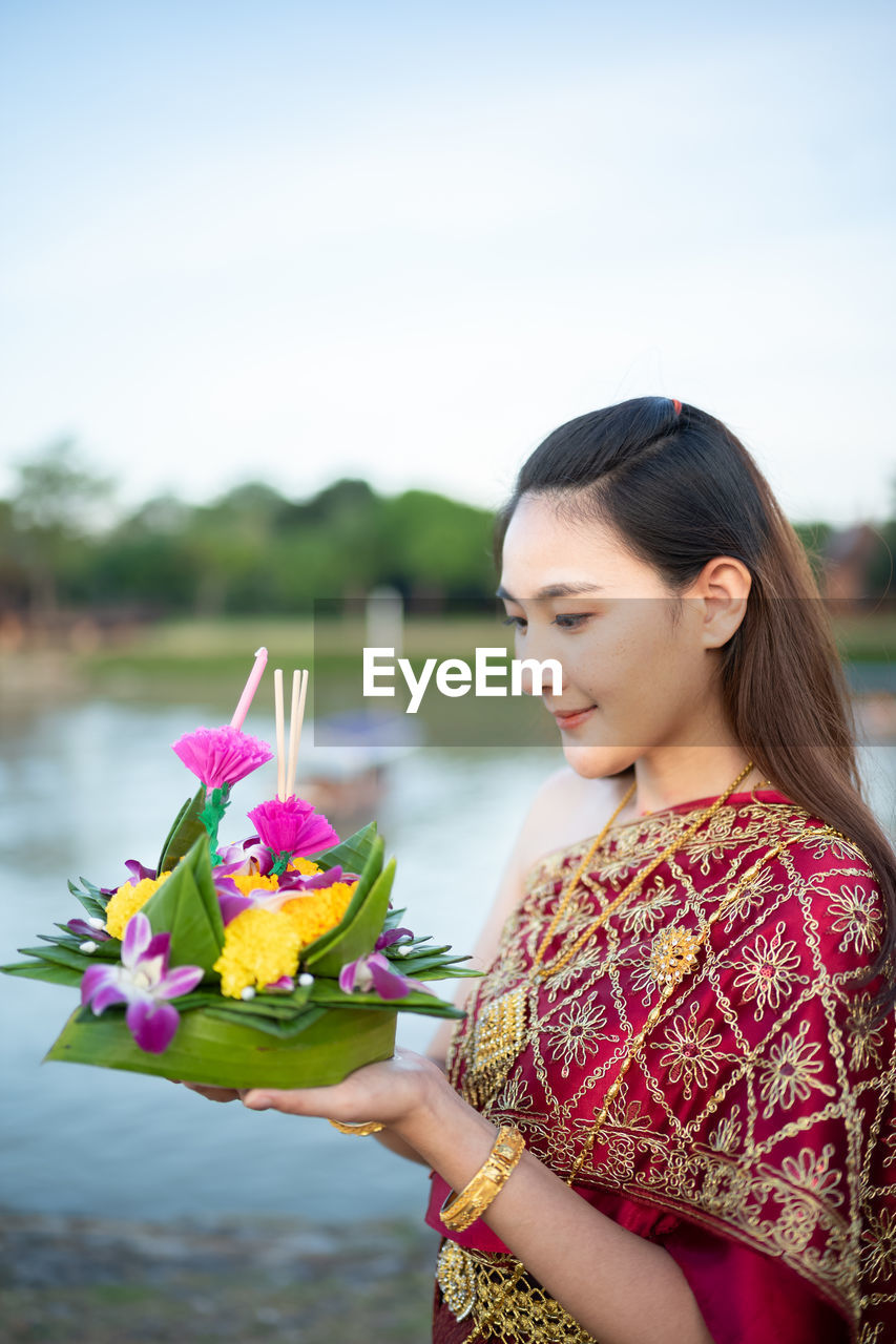 YOUNG WOMAN WITH PINK FLOWER AGAINST PLANTS