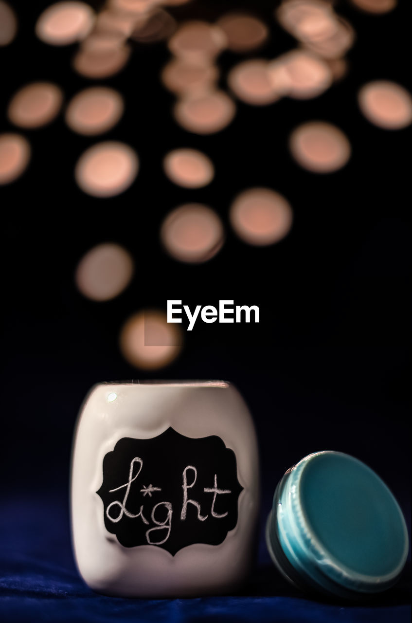 Close-up of text on container against illuminated lighting equipment