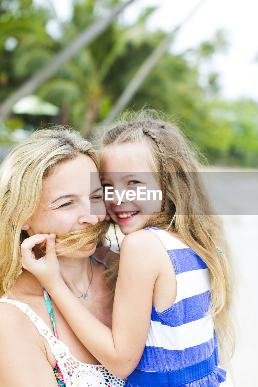 Portrait of smiling girl with mother at beach