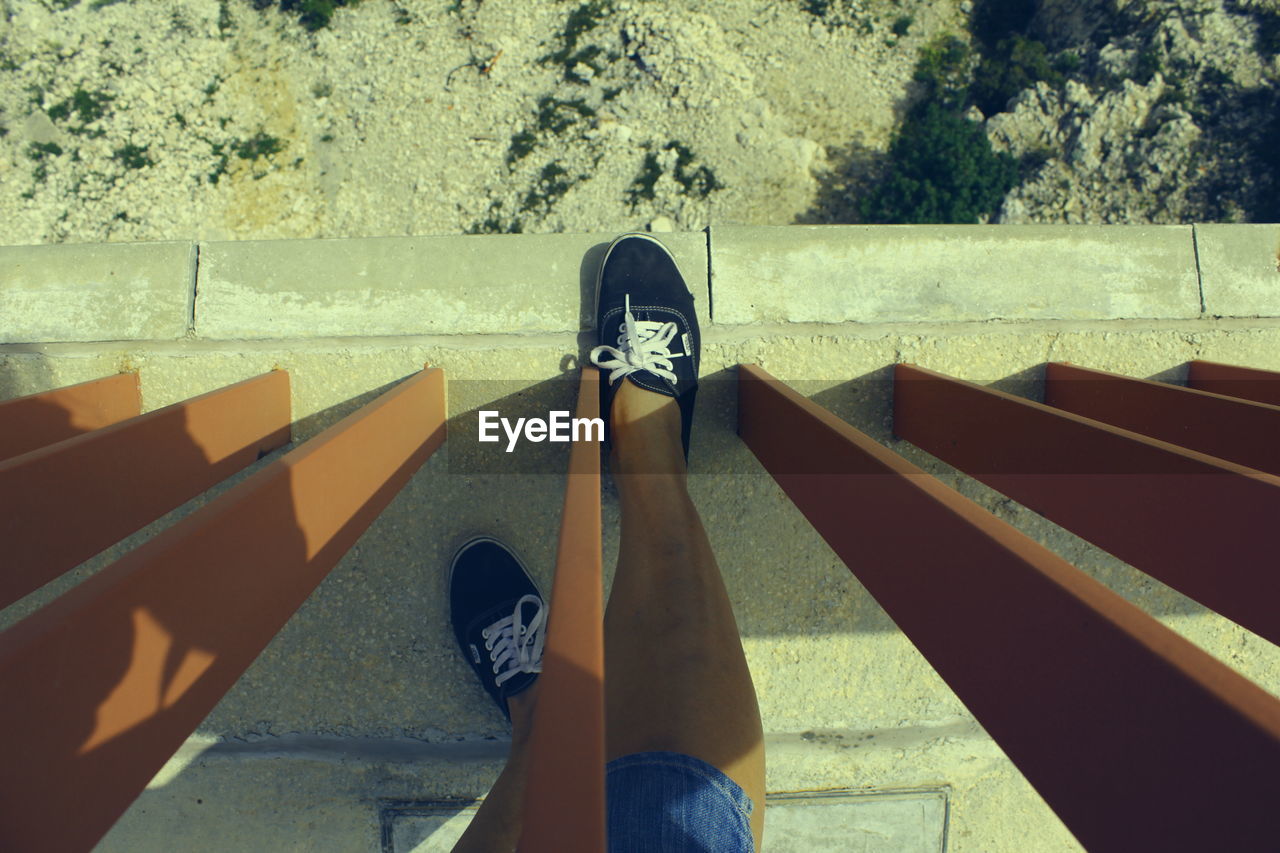 Low section of person standing on bridge during sunny day