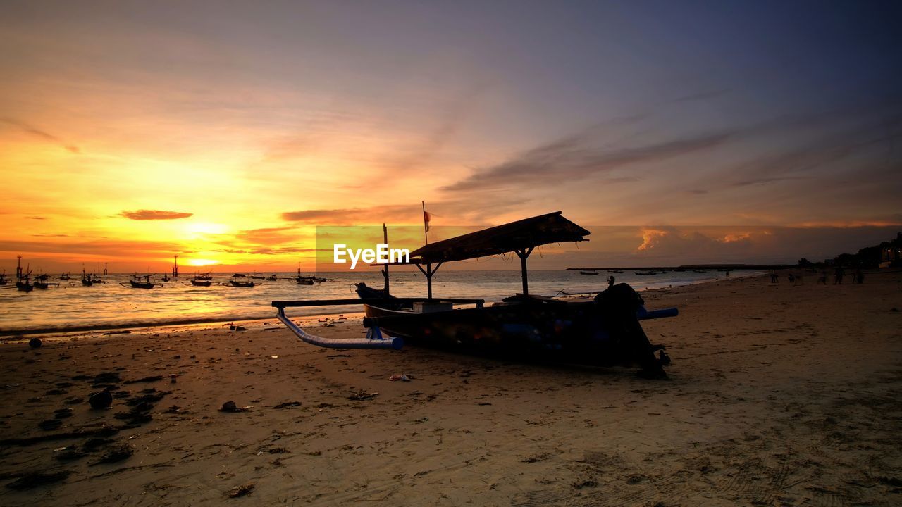 Scenic view of sea with local fisherman boat against sky during sunset