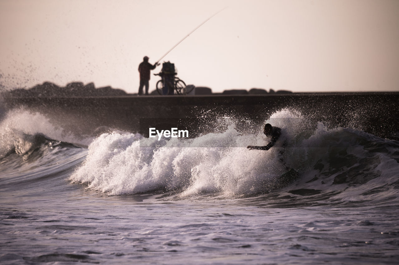 Man surfing in sea against sky