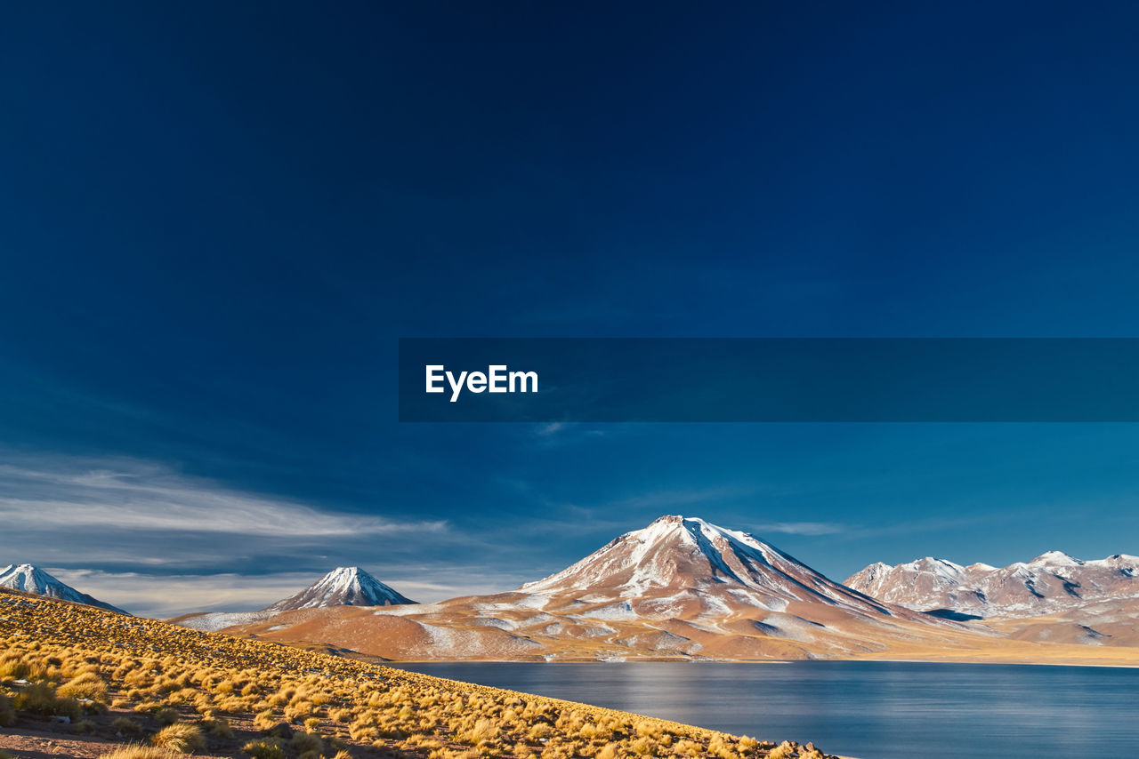 Scenic view of snowcapped mountains against blue sky