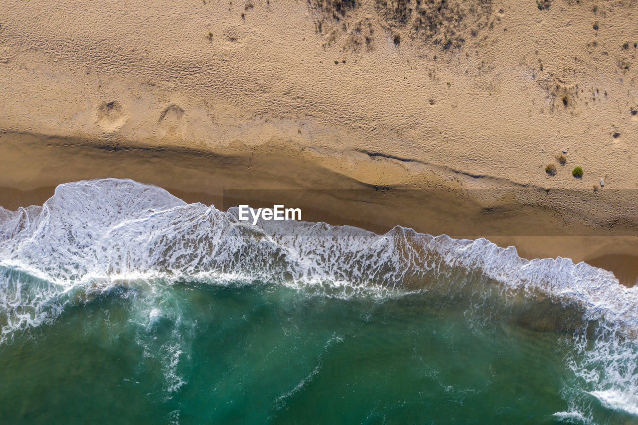 Aerial view of a remote sandy beach and sea waves by drone