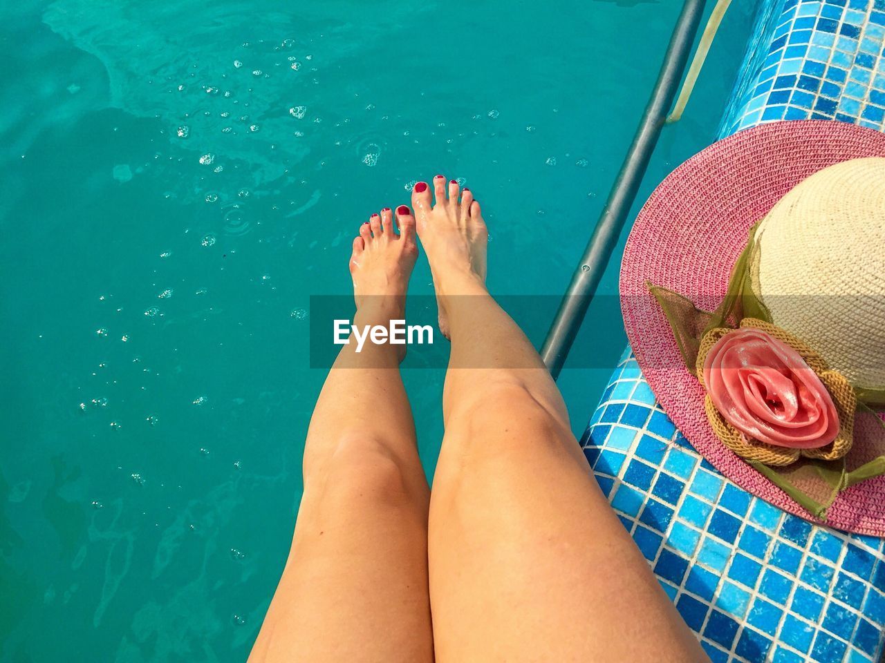 Low section of woman relaxing at swimming pool