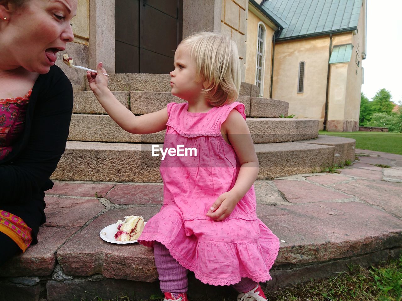 Portrait of cute girl feeding cake to woman