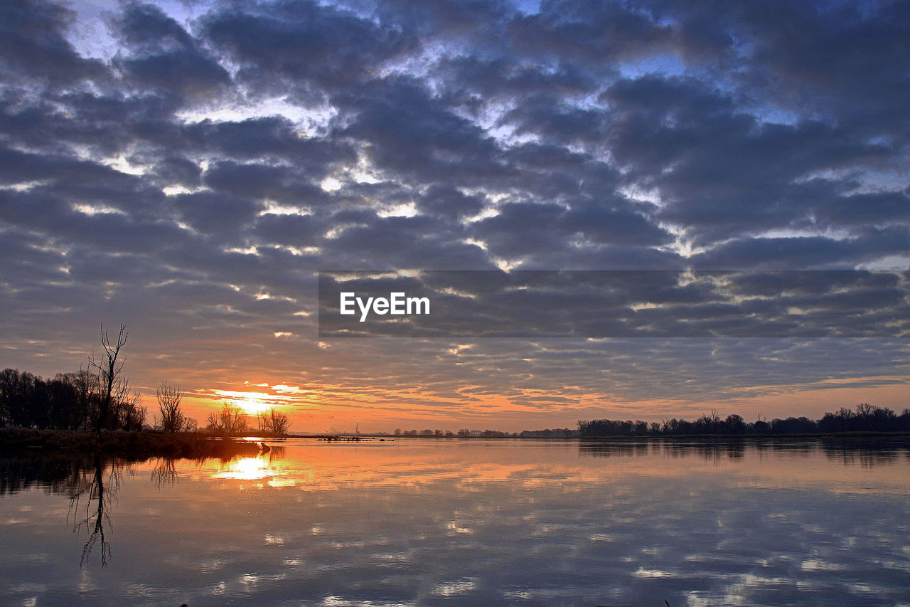 View of calm lake against cloudy sky during sunset