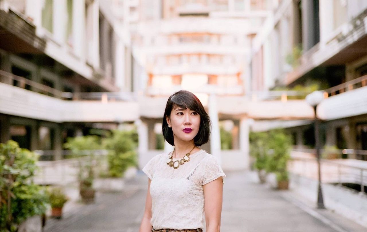 PORTRAIT OF WOMAN STANDING AGAINST WALL