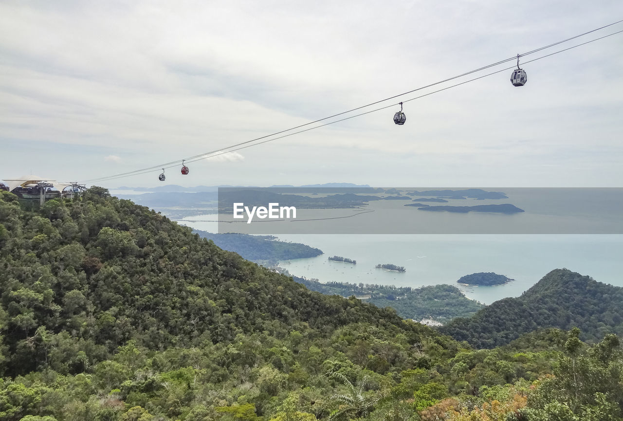 Overhead cable car over mountains against sky