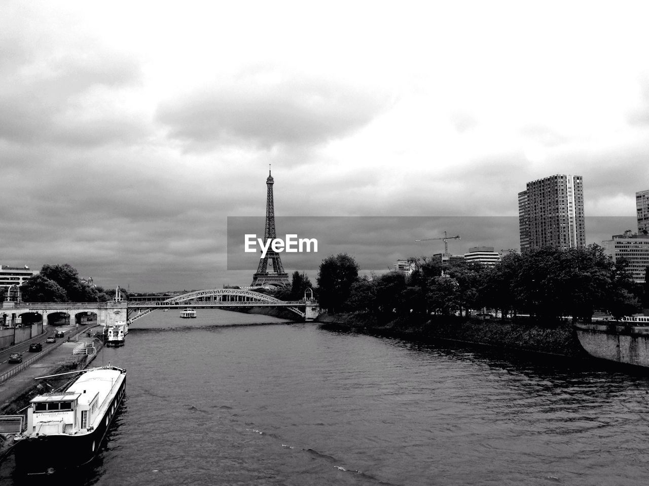 Boats moored on river with eiffel tower in background against sky