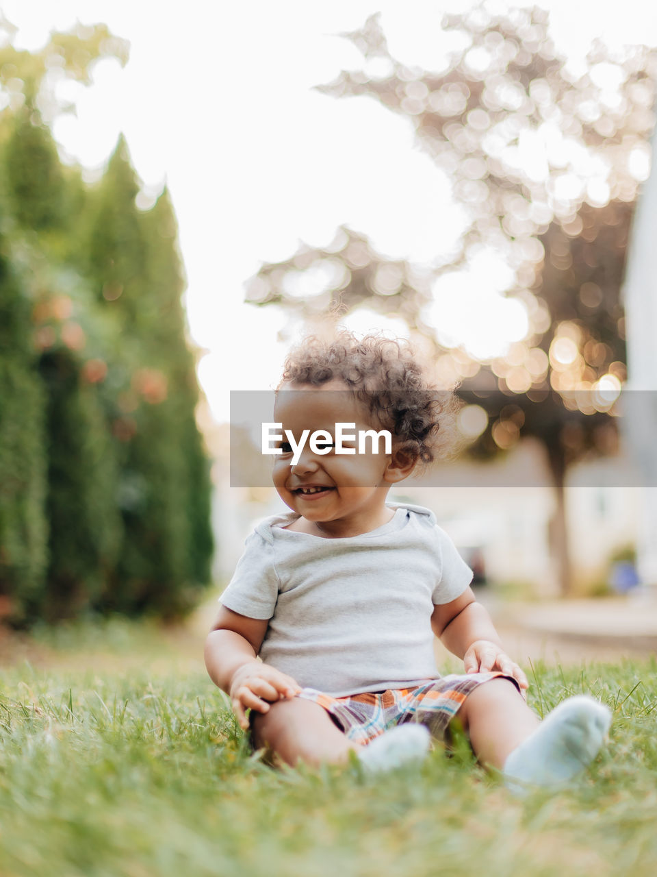 Smiling boy looking away while sitting at lawn